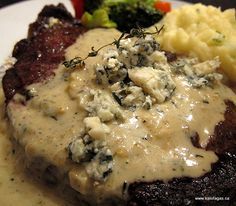 a white plate topped with meat covered in gravy and mashed potatoes next to broccoli