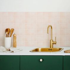 a kitchen sink with gold faucet and wooden utensils on the counter