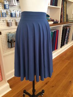 a mannequin wearing a blue skirt in front of a book shelf with books on it