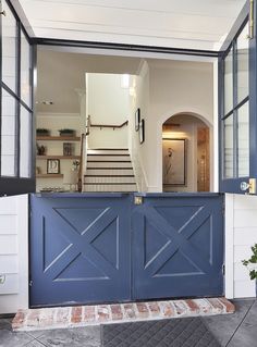 an open blue door leading to a house with stairs and potted plants in the doorway