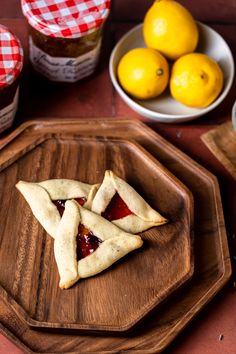 two pieces of pie sitting on top of a wooden cutting board next to lemons