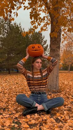 a woman sitting on the ground with her head in a jack - o'- lantern hat