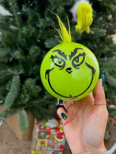 a person holding up a green ball with a face painted on it