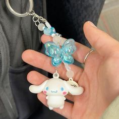 a person holding a keychain with an animal charm on it's side