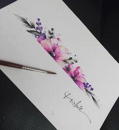 a piece of paper with watercolor flowers on it next to a pen and ink