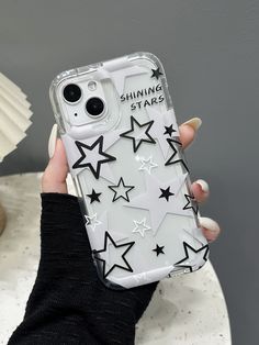 a woman holding up her phone case with stars on the front and bottom, while she is