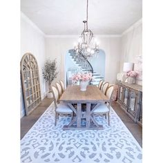 a dining room table with chairs and a chandelier hanging from the ceiling above it