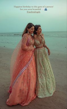 two women standing next to each other on a beach