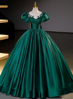 Dazzle the room with elegance in this luxurious emerald Quinceanera gown! Exquisite in its craftsmanship, the dress boasts a fitted bodice adorned with intricate floral appliques that cascade gently over the shoulders, creating an image of garden-esque splendor. The off-the-shoulder sleeves add a touch of classic romance, while the full, flowing skirt, crafted from sumptuous satin, creates a stunning silhouette that's both timeless and regal. Cinched at the waist with a ruched belt detail, this gown accentuates your figure before it balloons into a grandiose, floor-length skirt, ensuring every step you take is a statement of grace. This dress is not only a piece of clothing but a keepsake that embodies the celebration of youth and dreams blossoming into reality.Silhouette:ball gownHemline: Dresses Inspired By Disney Princesses, Fancy Dresses Wedding, Emerald Green Quinceanera Theme, Green Satin Prom Dress, Robes Quinceanera, Green Quinceanera Theme, Emerald Green Quinceanera, Formal Dress Short, Poofy Dresses