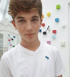 a young man standing in front of a wall with many colored cubes on it