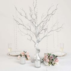 a white table topped with a vase filled with flowers next to a silver candle holder