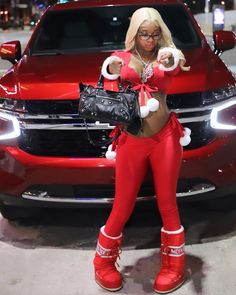 a woman in red and white outfit standing next to a red car with christmas decorations on it