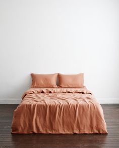 a bed with two pillows on top of it in a room next to a wall