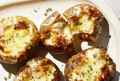 four baked potatoes with cheese and herbs on a plate