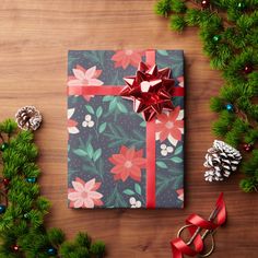 a wrapped present sitting on top of a wooden table next to pine cones and christmas decorations