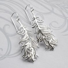 Our beautiful Sterling Silver Dangly Peacock Feather Earrings are bound to add glamour to any outfit! These gorgeous peacock feather earrings, make the perfect gift for someone who likes to stand out from the crowd. The peacock feather symbolises compassion and integrity, the perfect gift for someone who deserves a special thank you. We dont mind if you treat yourself either...we promise not to tell! Elegant Silver Feather Earrings, Elegant Peacock-colored Earrings As A Gift, Elegant Peacock Colored Earrings For Gift, Elegant Peacock-colored Earrings For Gift, Sterling Silver Feather Earrings Gift, Elegant Feather Earrings For Gift, Elegant Feather Jewelry As Gift, Elegant Feather Jewelry Gift, Elegant Feather Jewelry For Gift