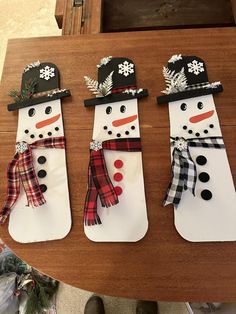 three snowmen made out of paper sitting on top of a wooden table