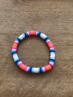 the multicolored beaded bracelet is sitting on a wooden table