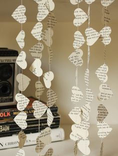 some paper hearts hanging from a string on a shelf next to books and a camera