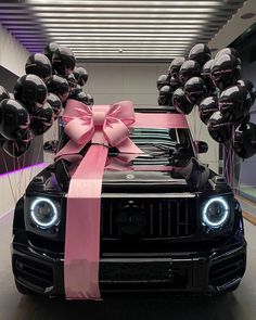 a black jeep with pink ribbon and balloons tied to it