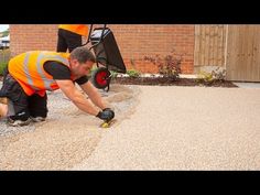 a man in an orange vest working on a driveway