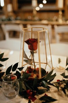 an arrangement of flowers and greenery on a table at a wedding or reception venue