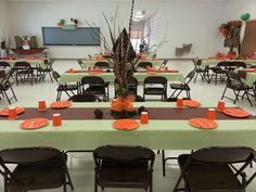 tables set up for an event with orange napkins and place settings on the table