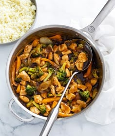 chicken and broccoli stir frying in a pan with rice on the side