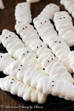 there are many white ghost cookies on the plate