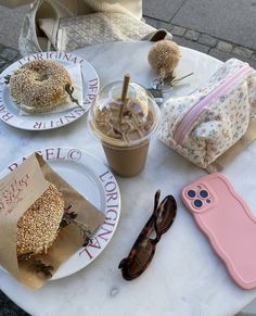 a table topped with donuts and coffee on top of it next to sunglasses, cell phone