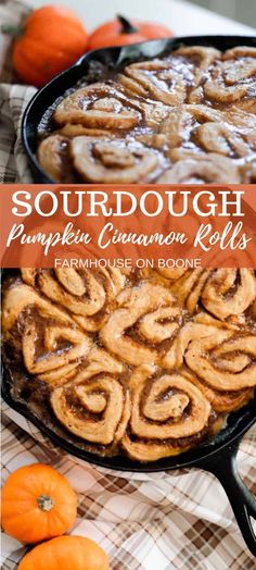 a pan filled with pumpkin cinnamon rolls on top of a checkered table cloth next to small pumpkins