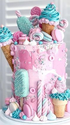 there is a pink and blue cake with ice cream cones on the top that are decorated in pastel colors