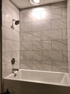 a white bath tub sitting under a bathroom light