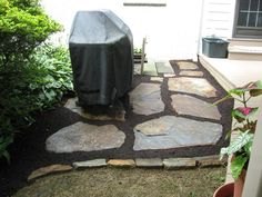 an outdoor patio with stone walkway and grill cover