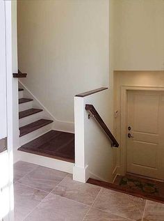 an empty room with stairs leading up to a door and a fire place in the corner