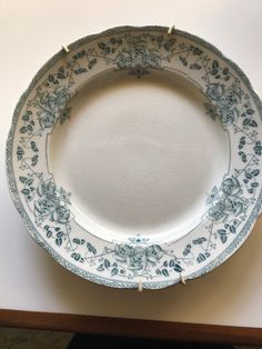 a white and blue plate sitting on top of a table next to a wooden frame