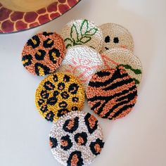 six crocheted animal print coasters sitting on a table next to a plate