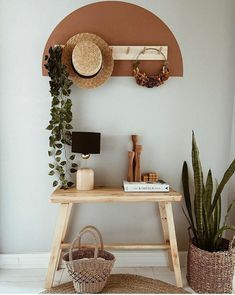 a wooden table topped with a basket next to a wall mounted shelf filled with plants