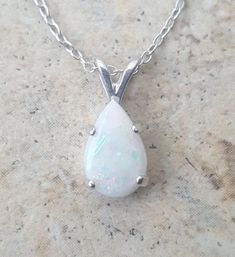 This lovely Opal drop necklace is Sterling Silver with an approx. 1 ct genuine Australian Opal, prong set in handmade settings..The Opal is a natural, AAA top quality Opal and exhibits good fire.The setting is hand made by me and is a strong prong setting which keeps the Opals in securely. The Opal Necklace is approx. 1/2 long. (from the top of the bale to the bottom of the stone.)The chain is a durable cable chain and looks great with the Opal pendant.Opal is the birthstone for October.Please n White Oval Necklace With Prong Setting, Classic White Pear Solitaire Necklace, White Teardrop Jewelry With Prong Setting, White Teardrop Solitaire Necklace For Formal Occasions, Classic Oval Drop Necklace Gift, White Round Drop Necklace For Anniversary, Classic Oval Drop Necklace For Gift, Formal White Teardrop Solitaire Necklace, Classic White Pear-shaped Solitaire Necklace