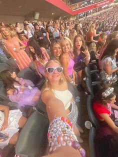 a group of women sitting next to each other in front of a crowd at a baseball game