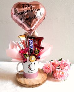 a coffee mug filled with chocolates, candy and foil heart balloons on a table