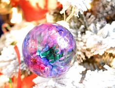 an ornament hanging from a christmas tree in front of some white branches and snow