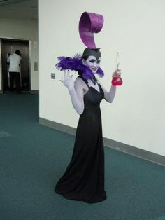 a woman dressed in black and purple is holding a wine glass with a pink hat on her head