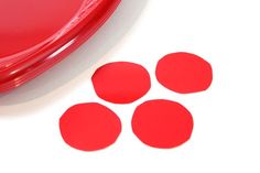 four red circles sitting on top of a white surface next to a plastic container with the lid open