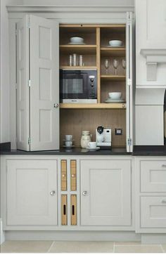 a kitchen with white cupboards and black counter tops in front of a microwave oven