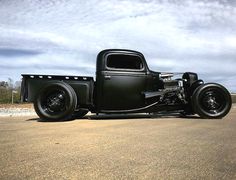 an old black truck is parked in the dirt