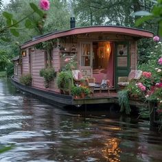 a houseboat is floating down the river with flowers on it's deck and patio