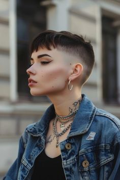 Person with short hair, multiple piercings, and tattoos wearing a denim jacket in front of a building. Woman Shaved Head, Grunge Pixie Haircut, Shaved Head Styles, Goth Hairstyles