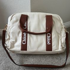 a white purse with brown straps and the words one, one, one on it