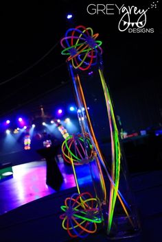 a tall glass vase filled with colorful neon colored stringy rings on top of a wooden table